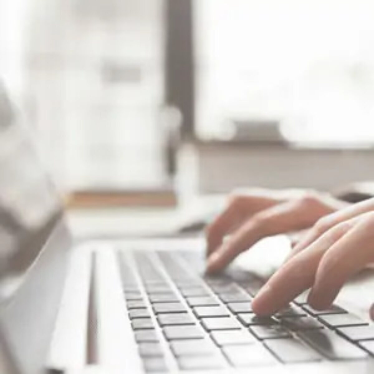 Hands typing on a laptop keyboard