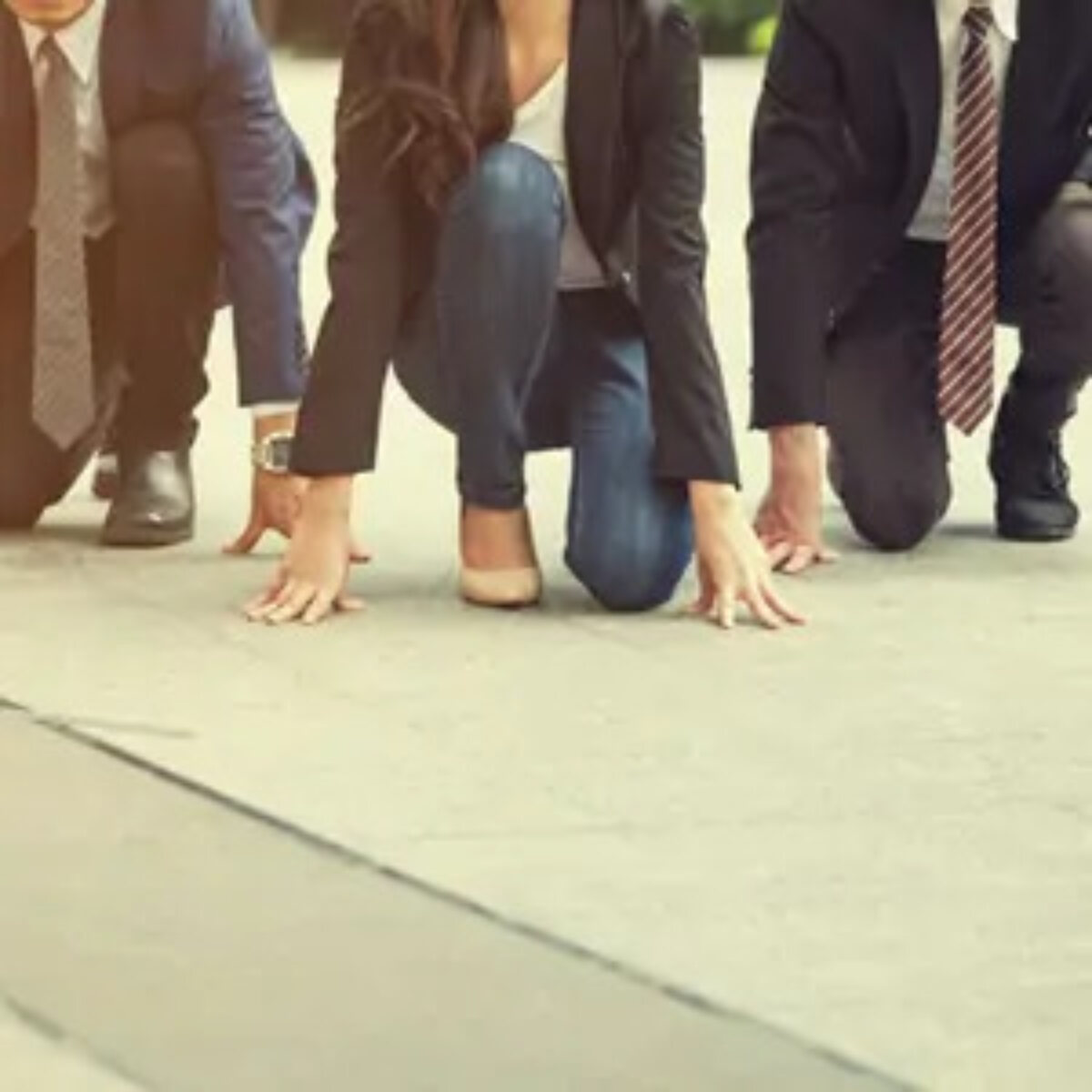 Three businesspeople crouching on ground as if about to start a race
