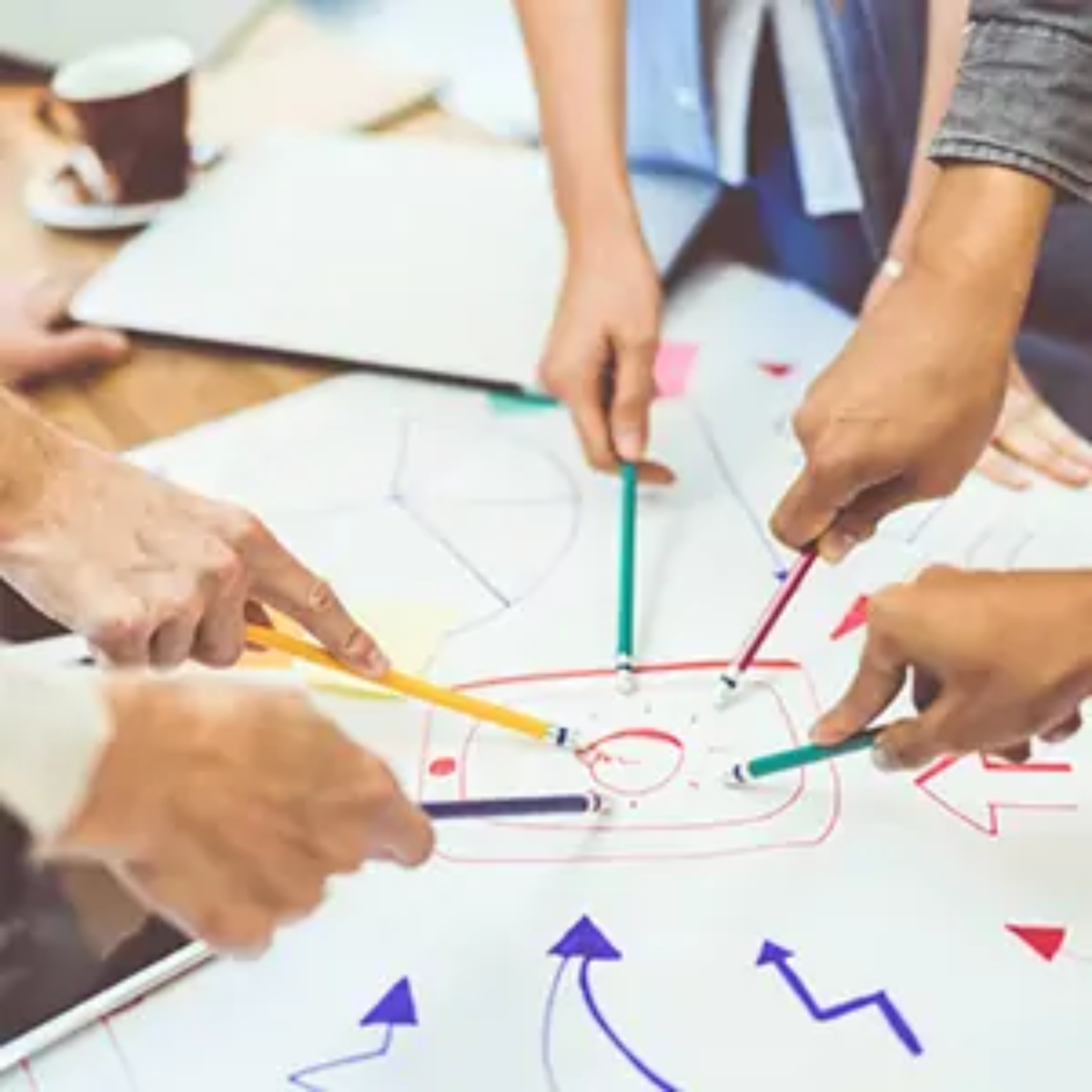 Businesspeople pointing at same point on business goals diagram with pencils