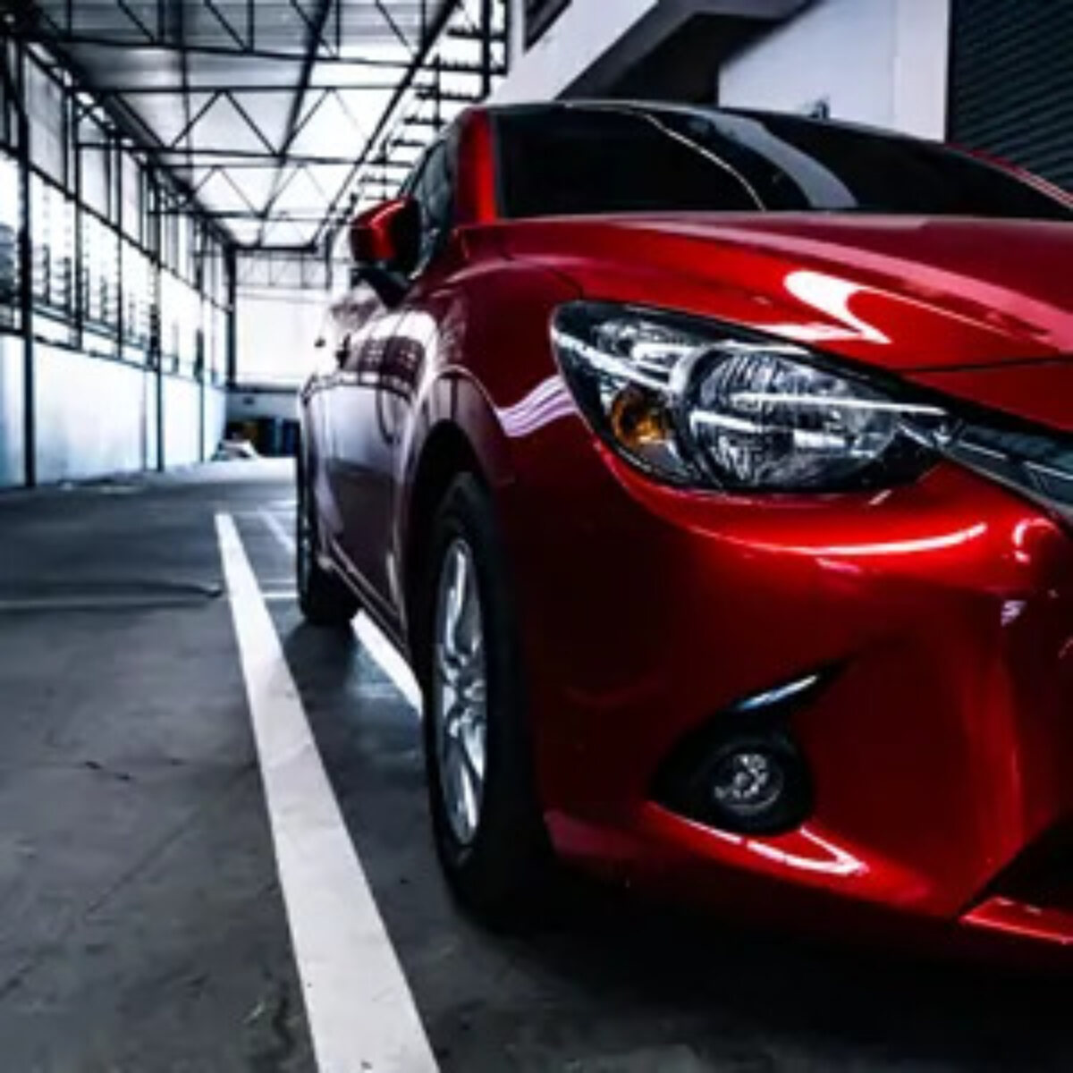 Close up of the side of a red car and the road