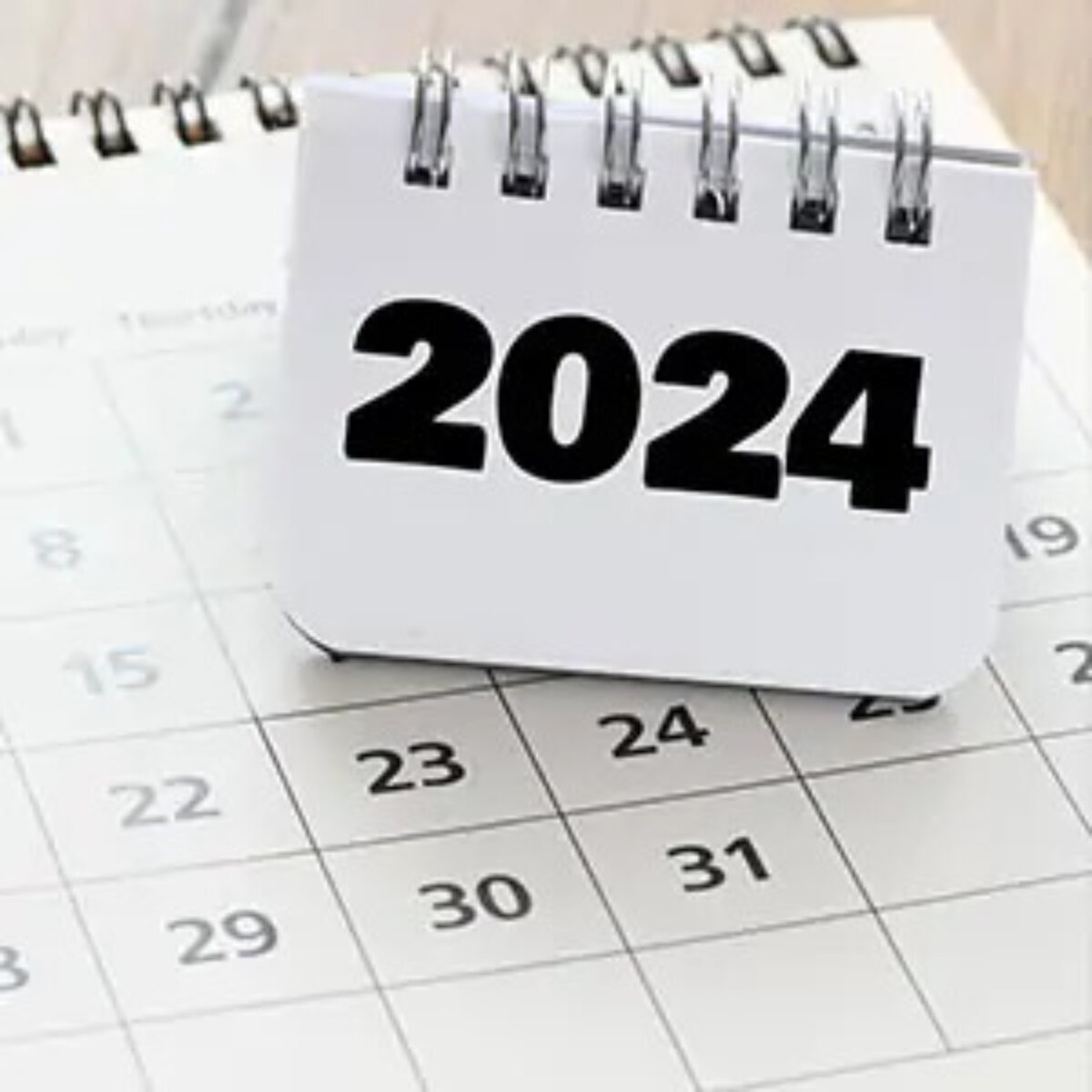 Calendar page with smaller ring bound notebook balanced on top reading '2024'