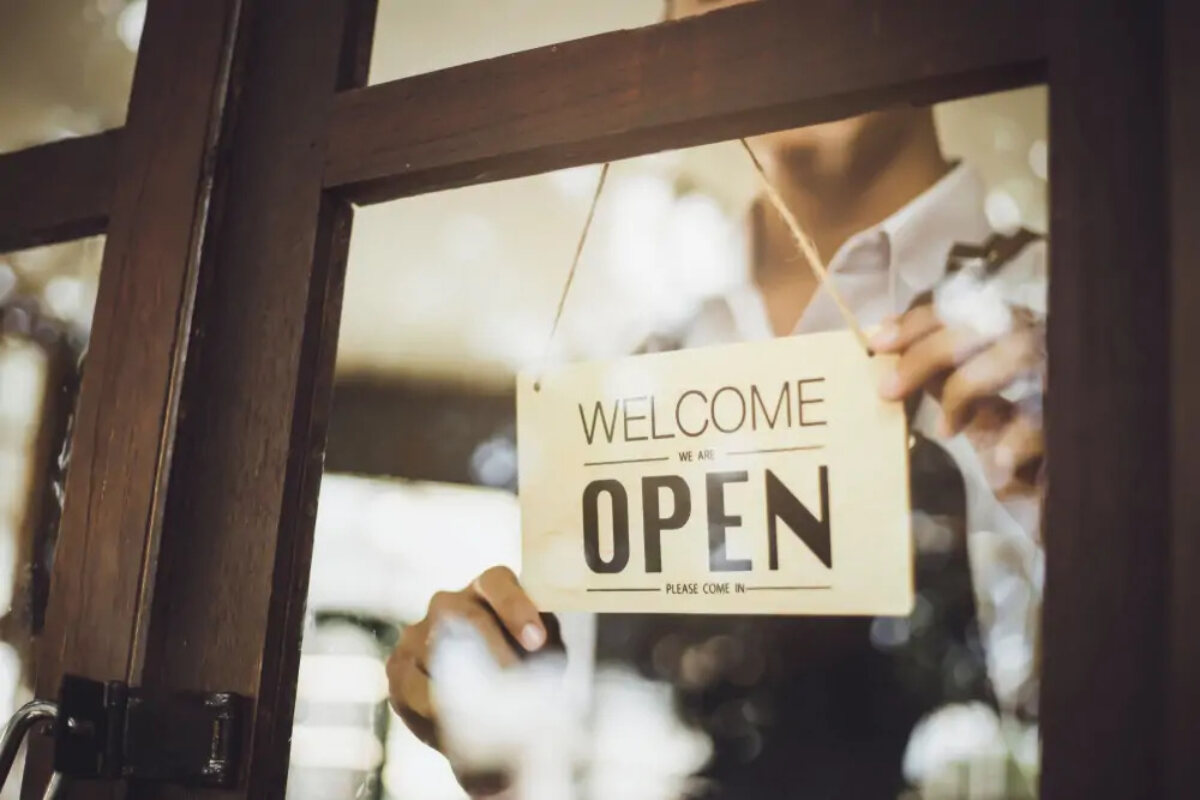 Business owner turning 'open' sign through glass door