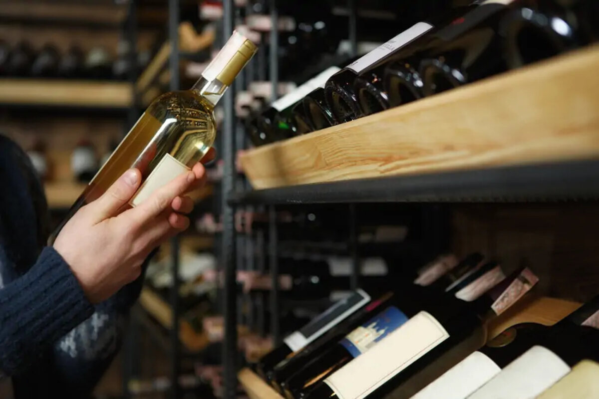Customer in shop holding bottle of white wine in wine section