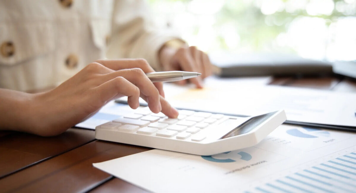 Businesswoman holing pen in hand and using calculator