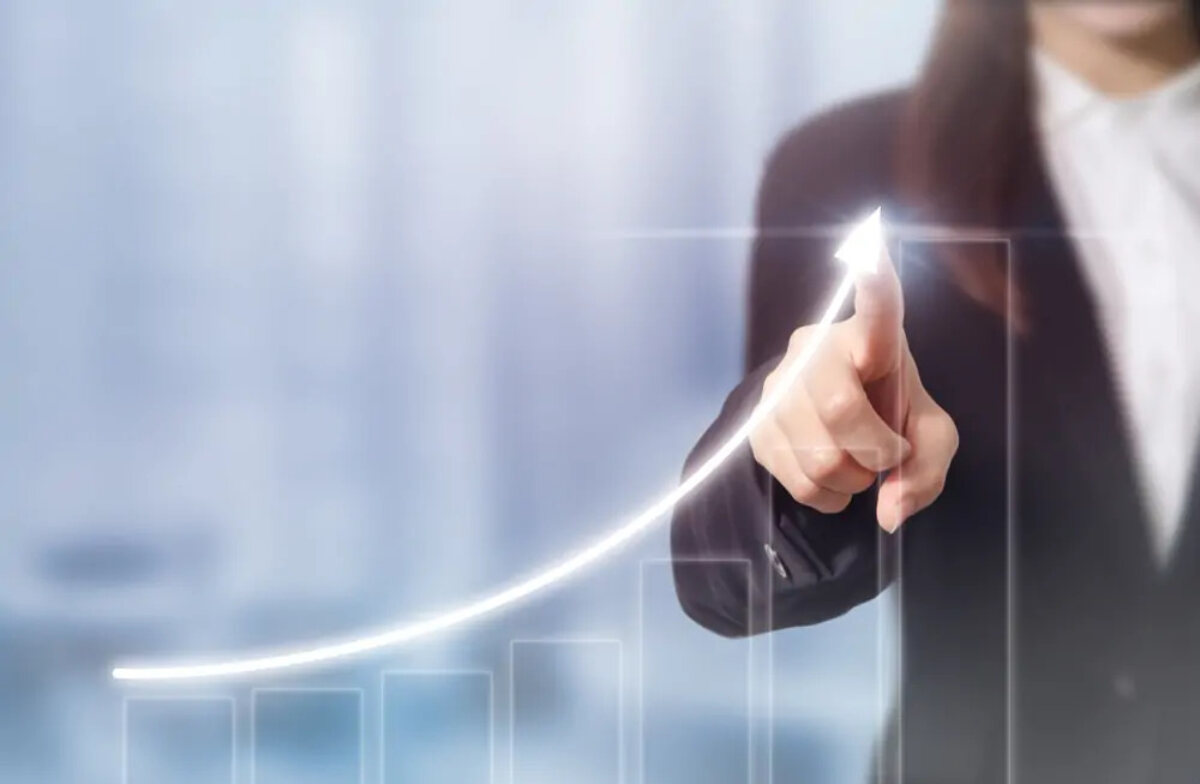 Businesswoman pointing at image of upwards arrow above an increasing bar chart