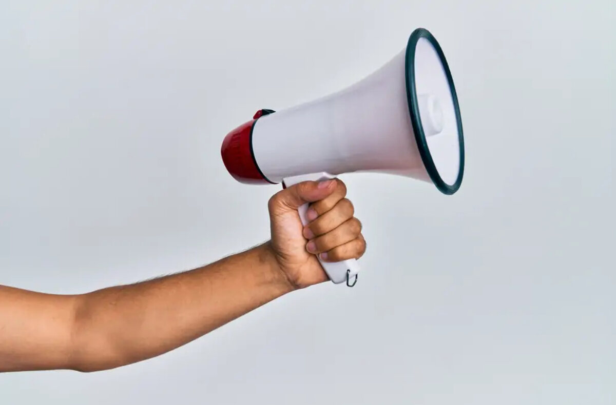 Outstretched arm with hand holding megaphone