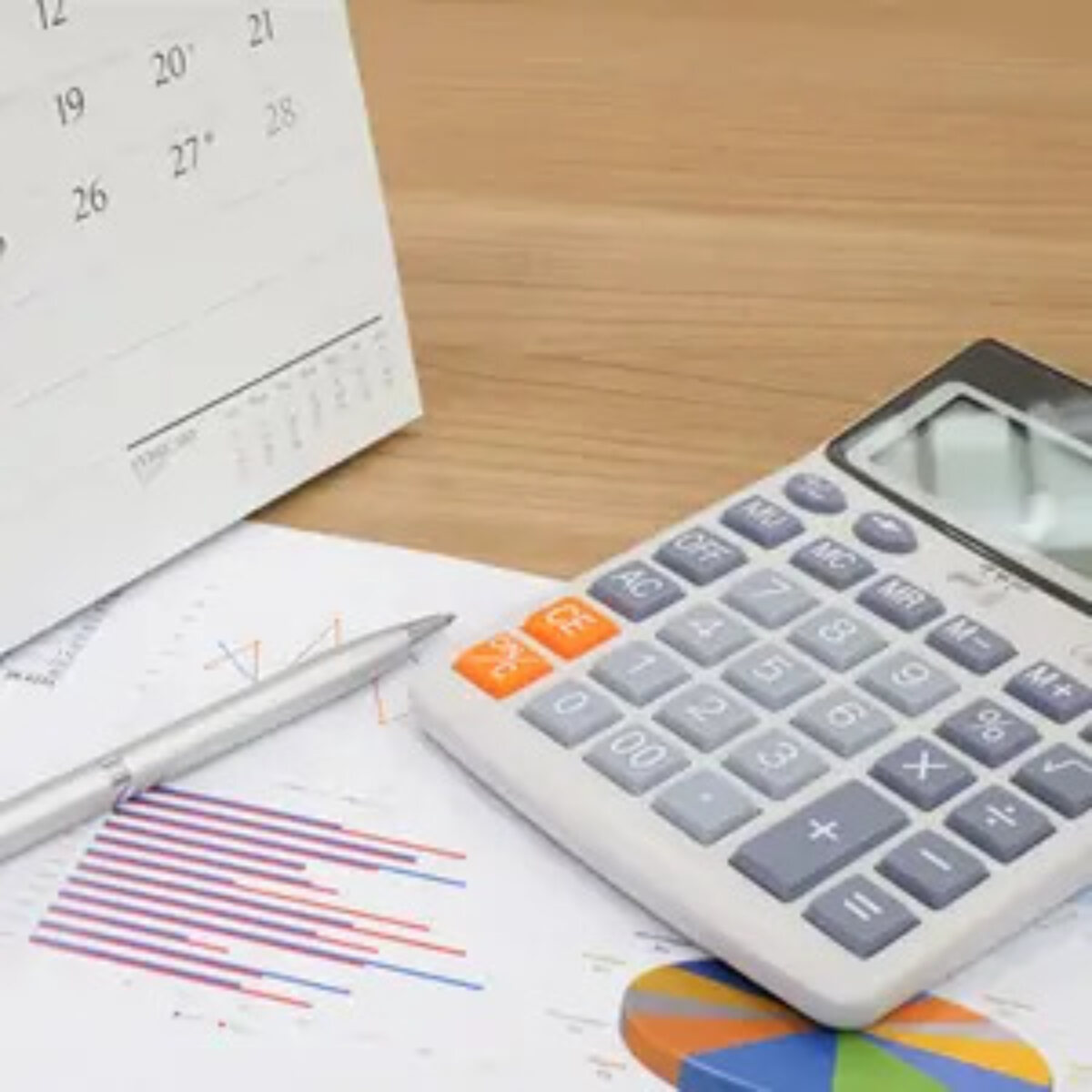 Calculator, pen and calendar on top of graph sheets