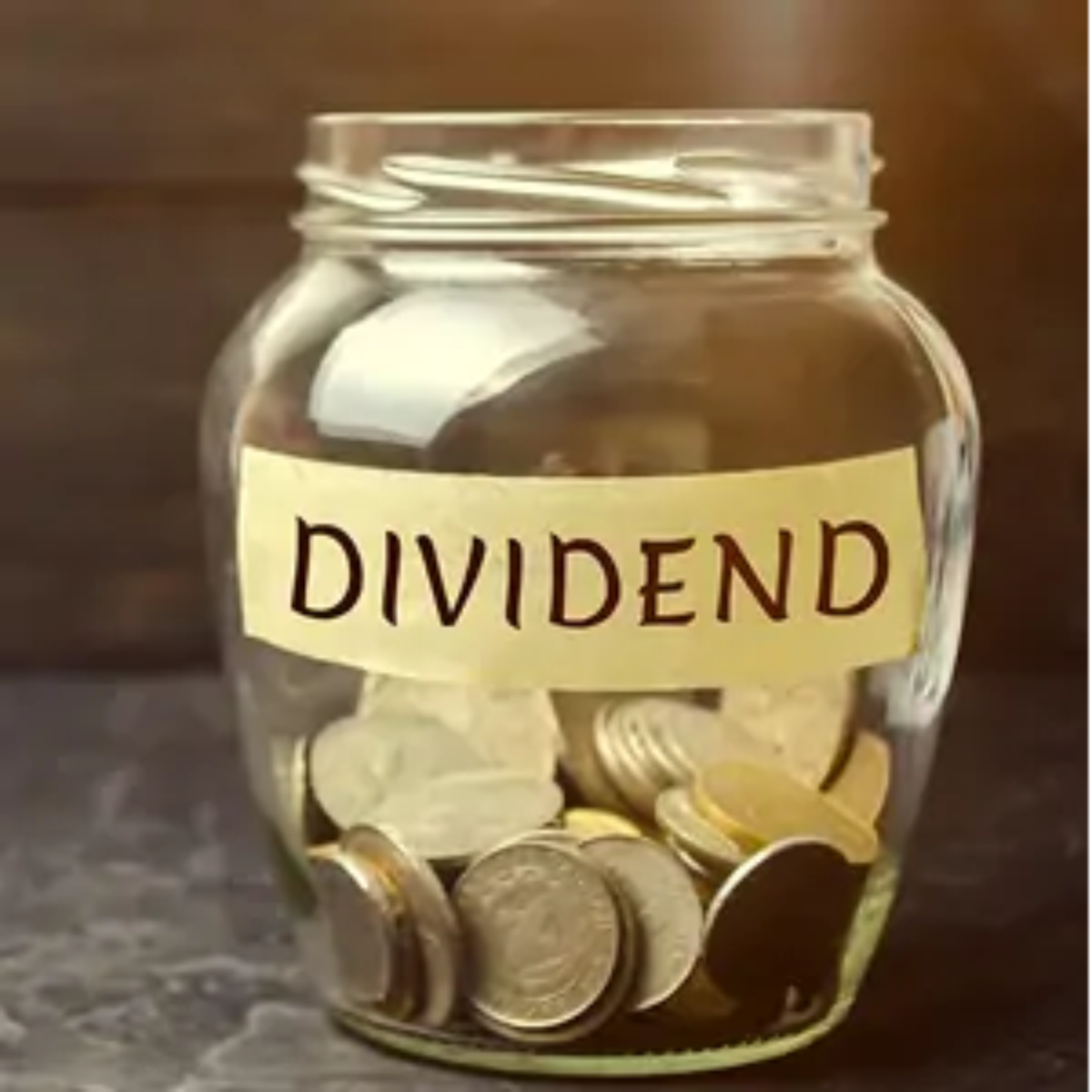 Glass jar half-filled with coins with 'dividend' label on front