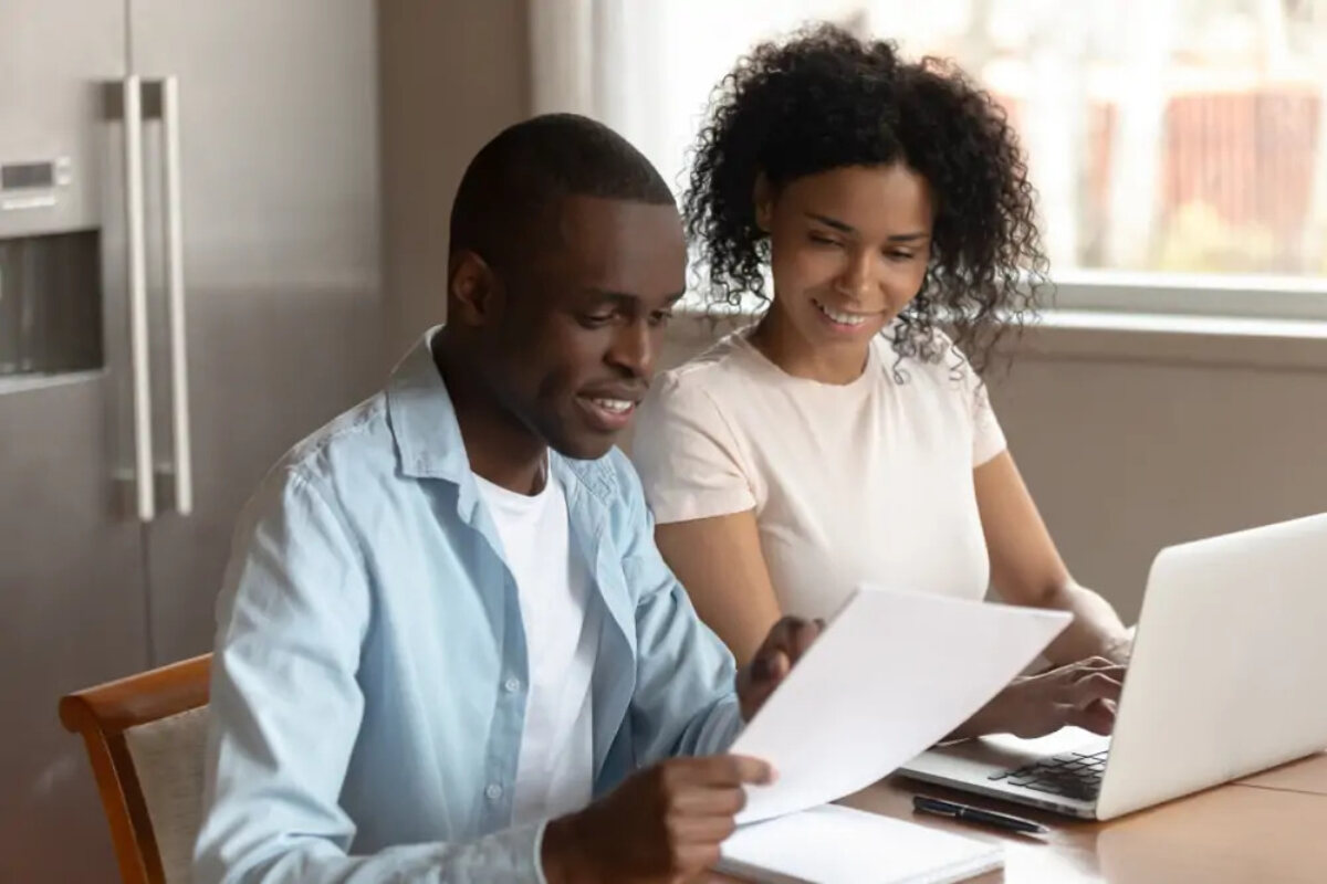 Couple sitting at table with laptop and documents looking at Income Tax