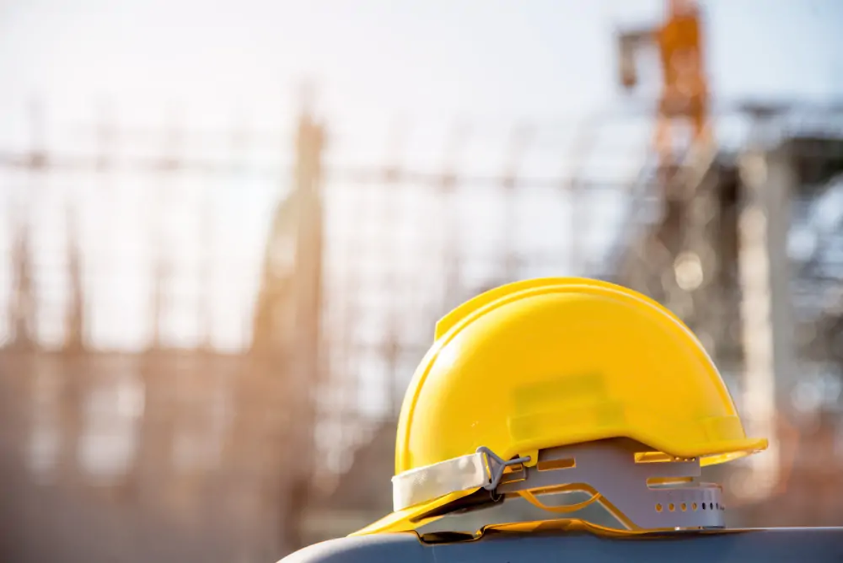 Yellow hard hat in foreground with construction site in background