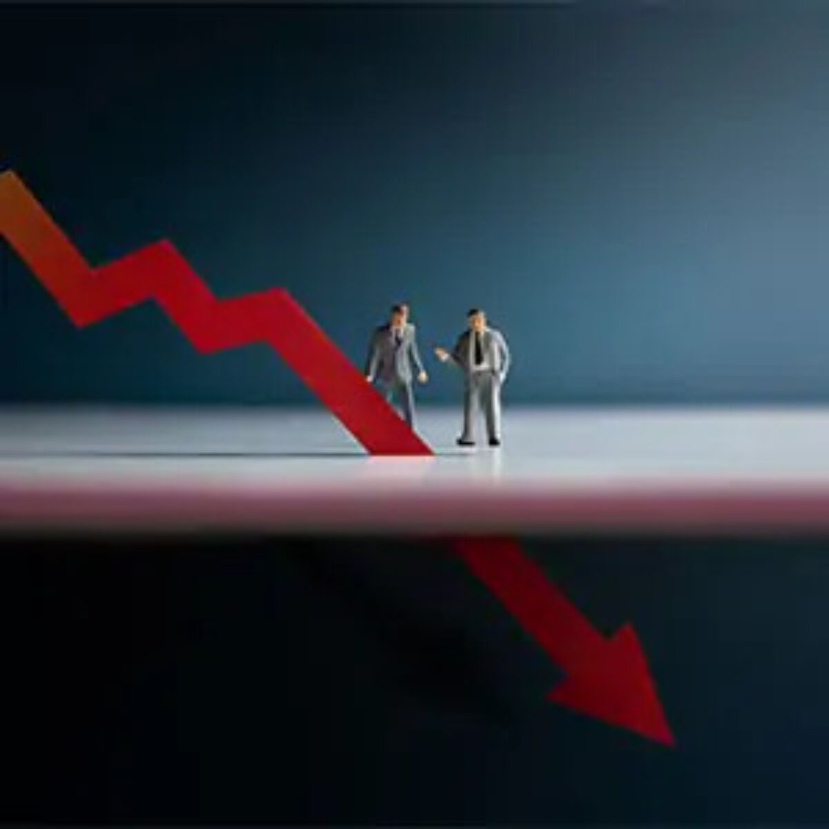 Businessmen figurines standing behind a downwards arrow that extends below surface they are standing on