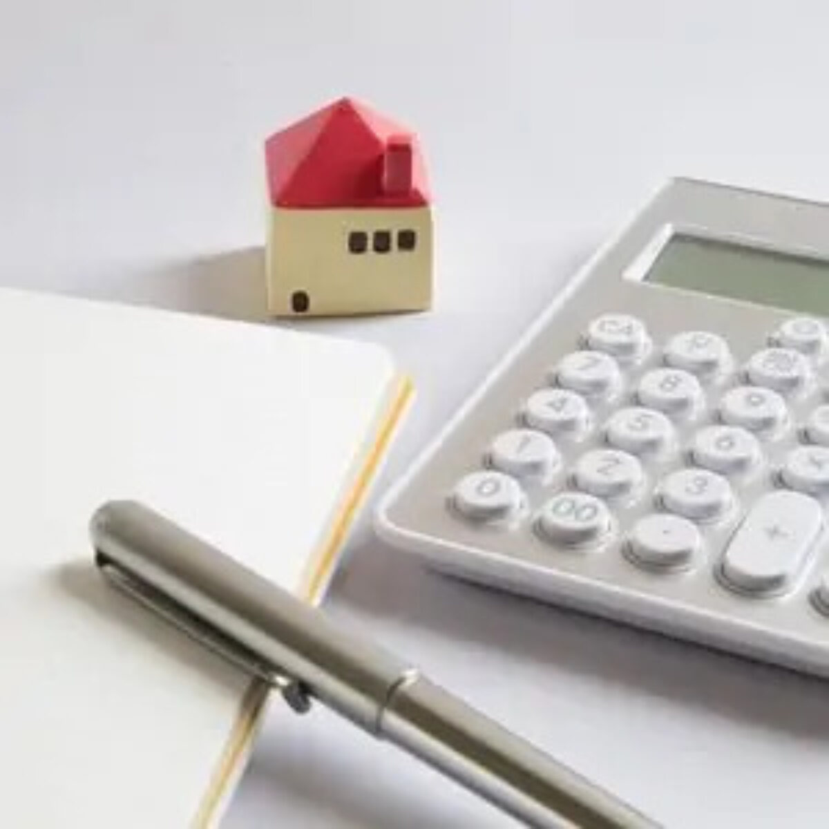 Empty notebook and pen, miniature model house and calculator