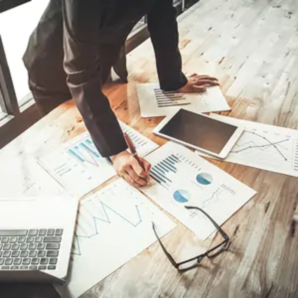 Businessman standing over table writing on balance sheet document