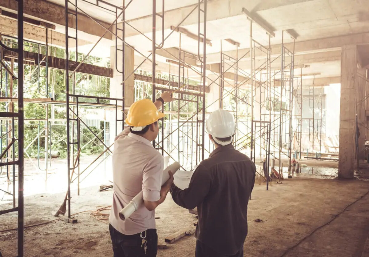Two men in business clothing wearing hard hats at a construction site