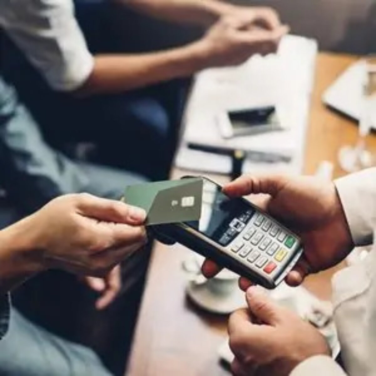Person using bank card to make a contactless payment at card machine
