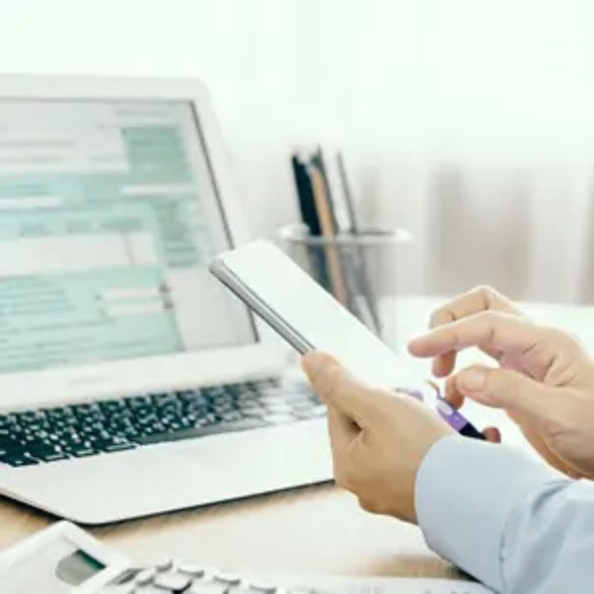Businessman using smartphone at desk in front of open laptop