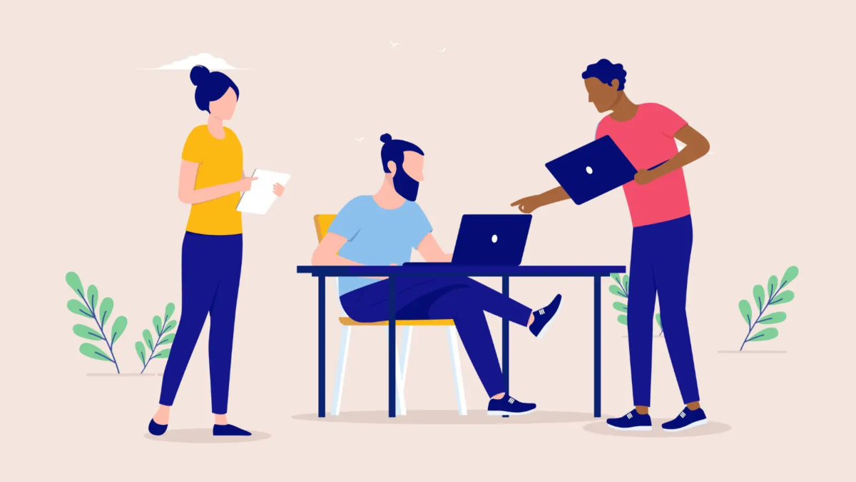 Cartoon of businessman working on laptop at desk and two businesspeople standing by desk with a laptop and document talking to him