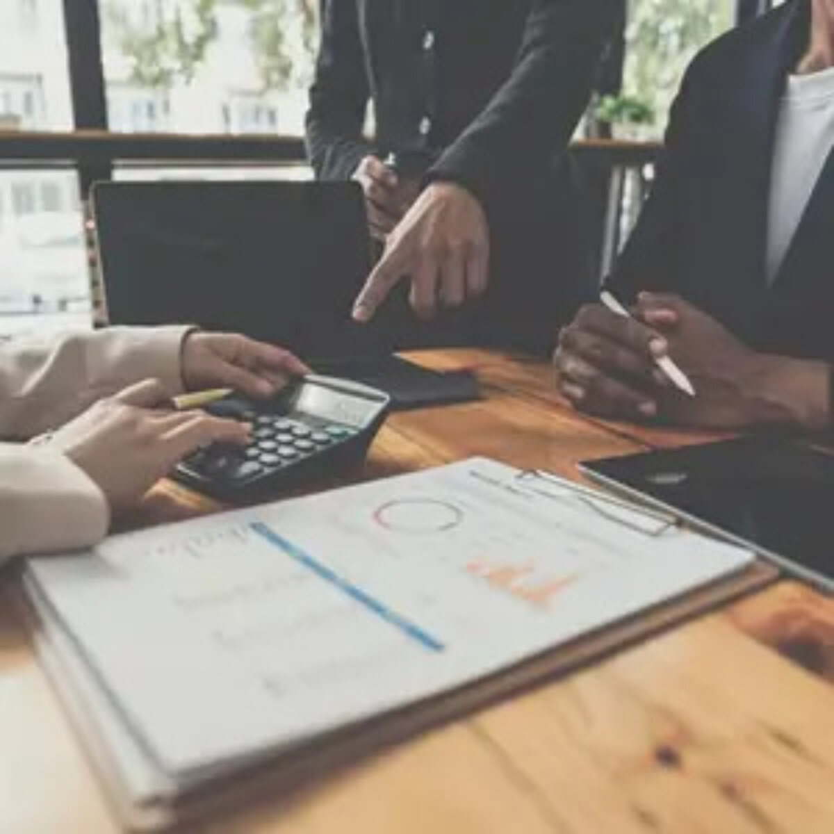 Businesspeople around table with calculator and printed documents calculating Corporation Tax