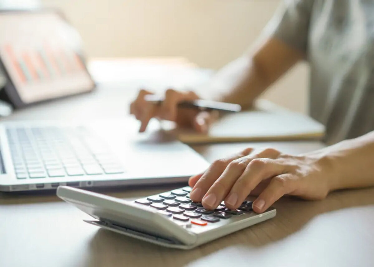Woman using calculator with one hand and laptop with the other