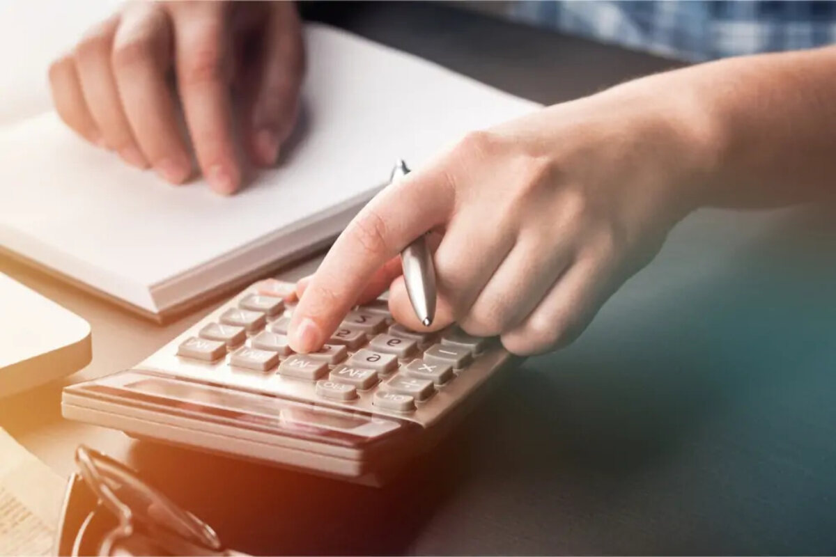 Businessman using calculator with pen in hand