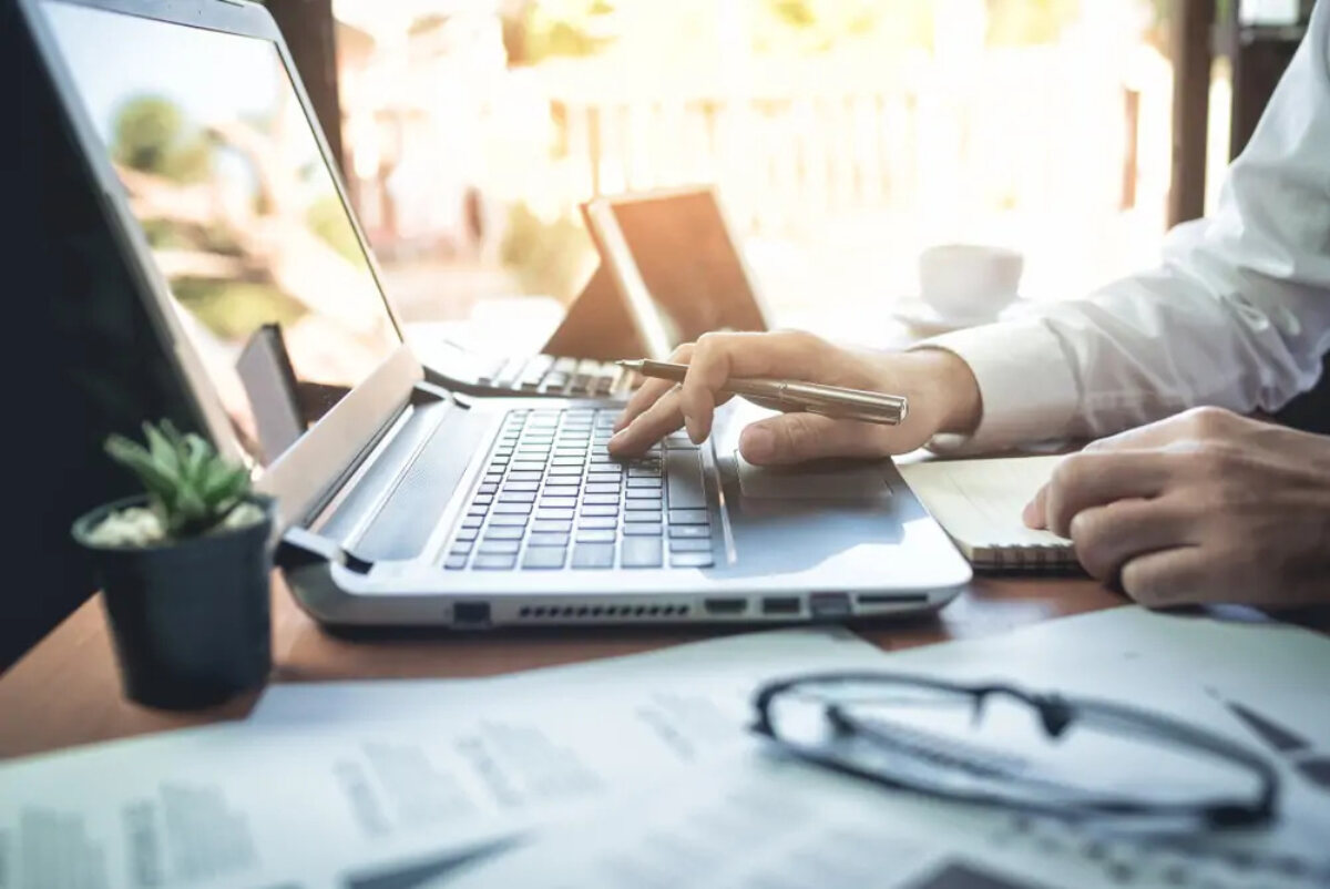 Businessman holding pen and using laptop