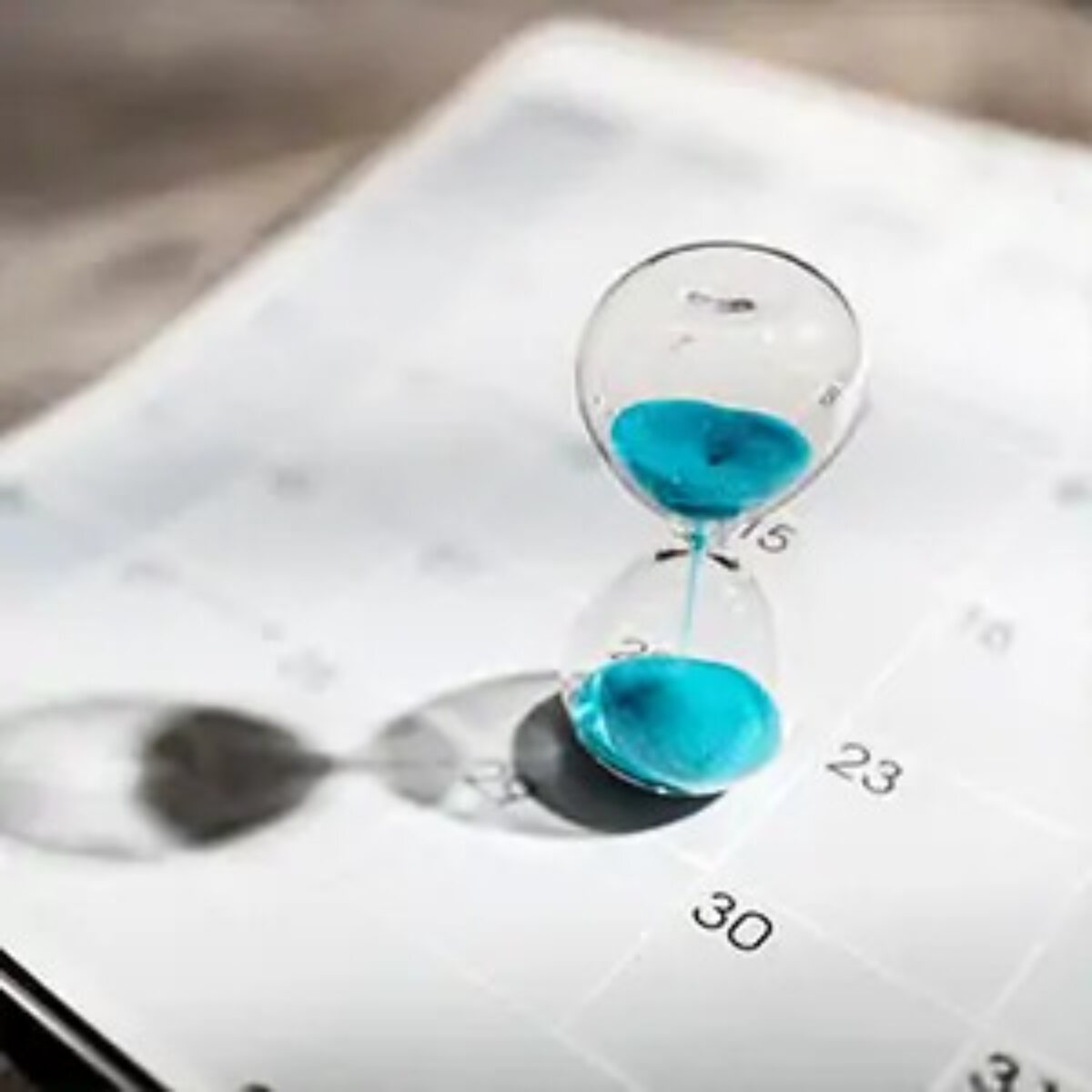 Sand timer in progress sitting on top of calendar page