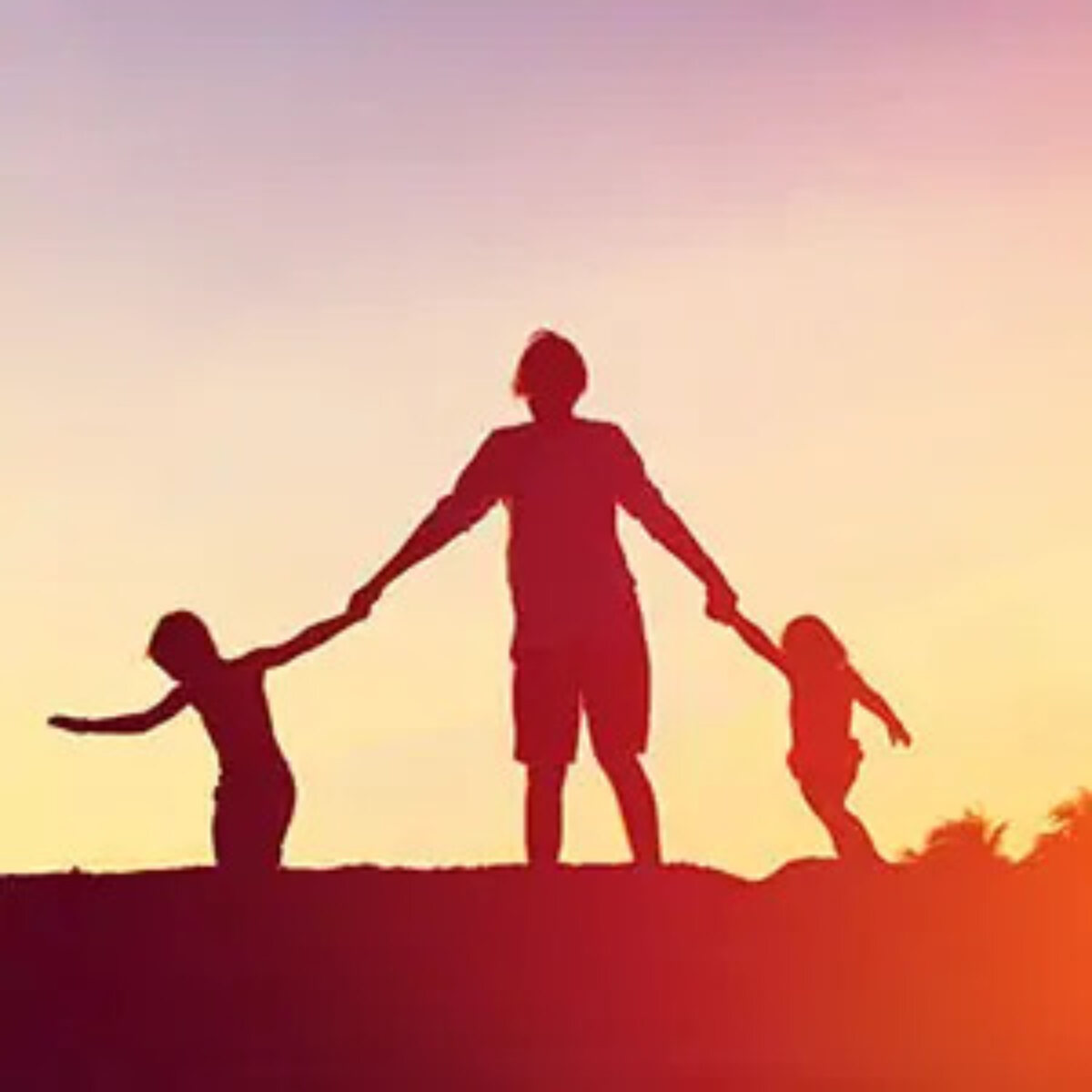 Silhouettes of a parent holding hands with two children against sunset