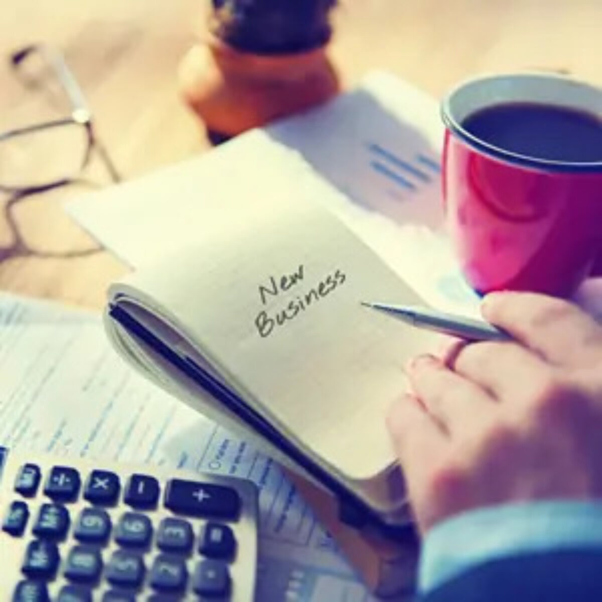 Businessman holding pen over open notebook with 'new business' written on the page