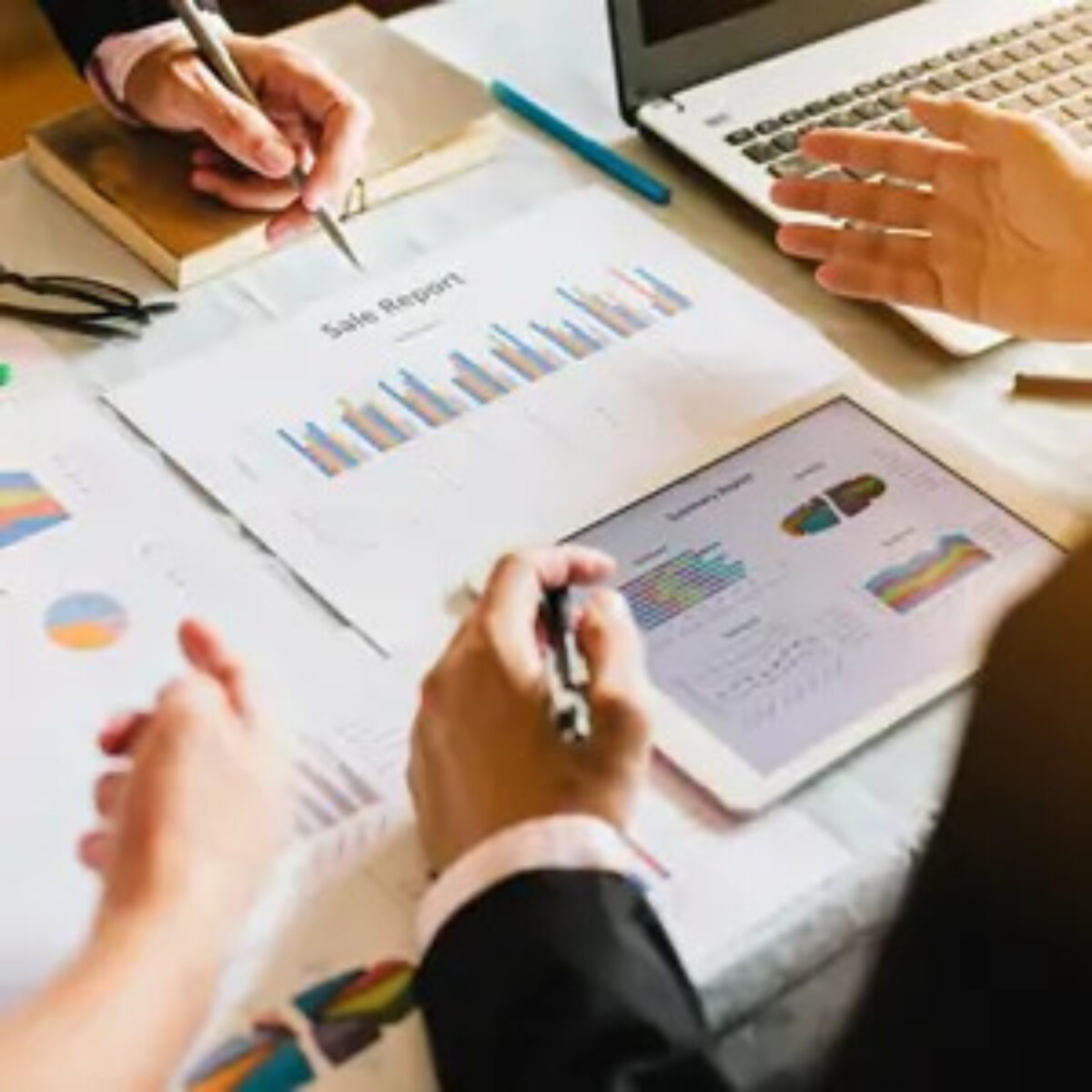 Businesspeople discussing sales report document at desk