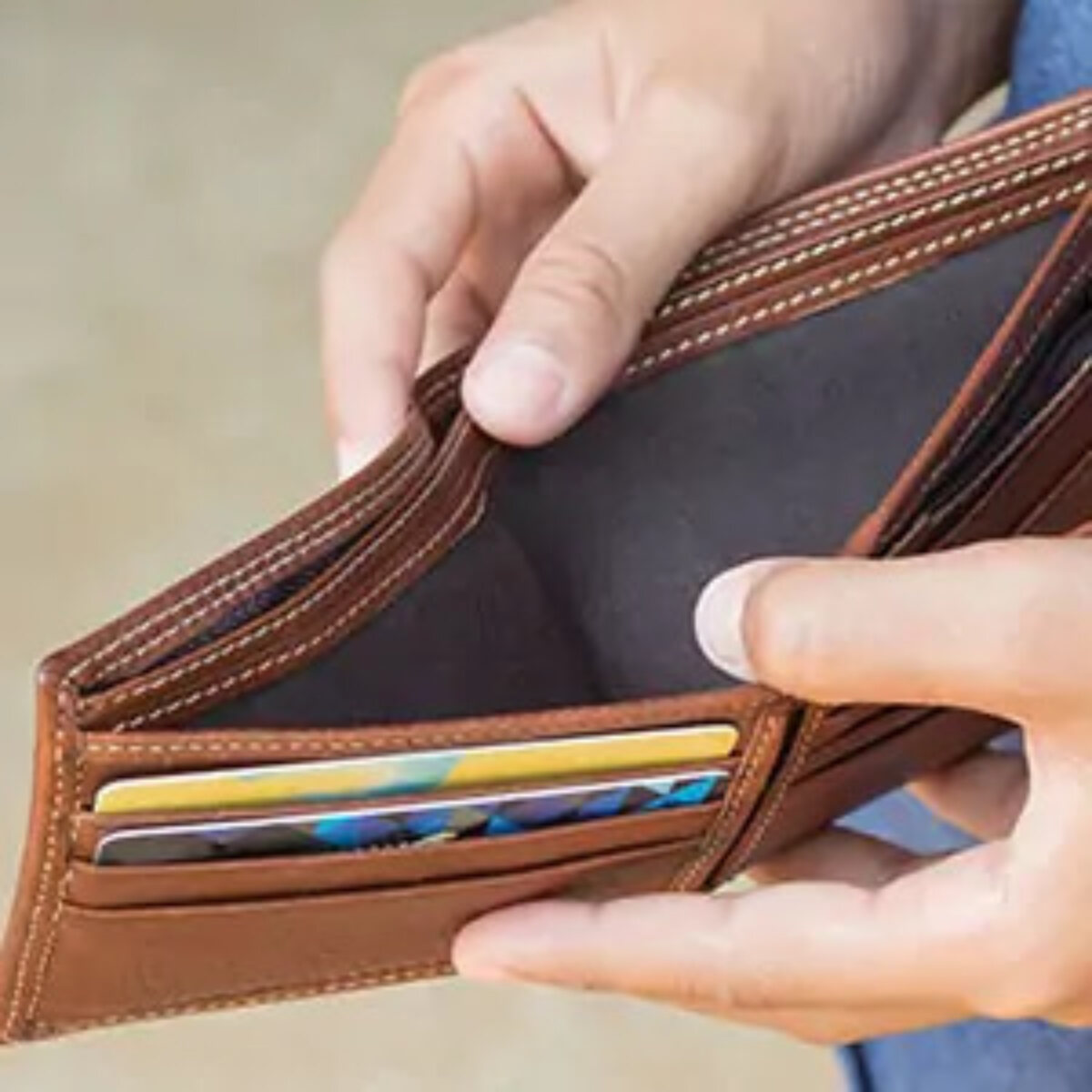Man holding open wallet with no cash inside and two cards in slots