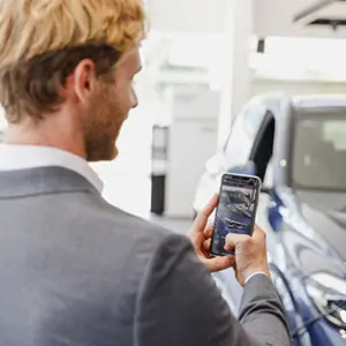 Man using smartphone to take a photo of a car