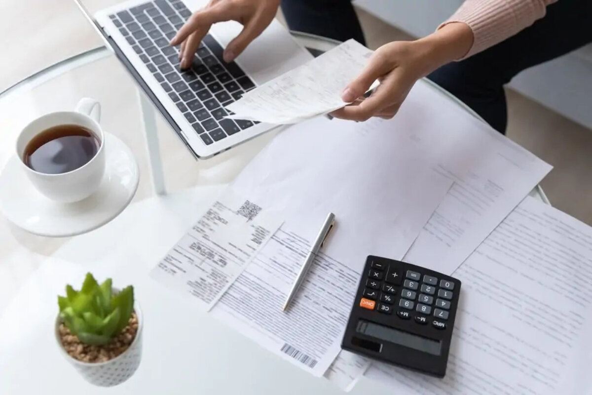 Businesswoman working on laptop on table next to documents and calculator
