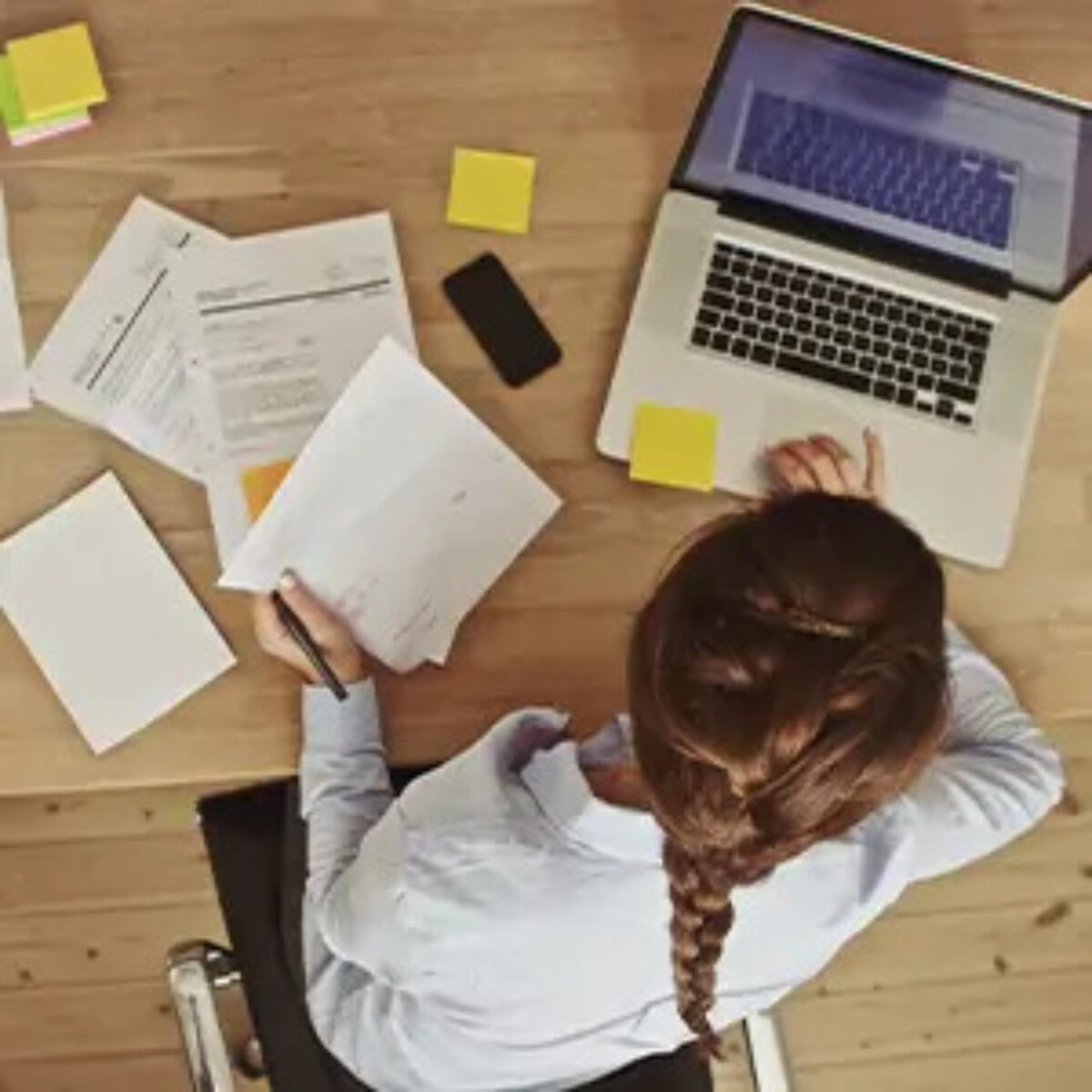 Businesswoman working on laptop at desk with papers