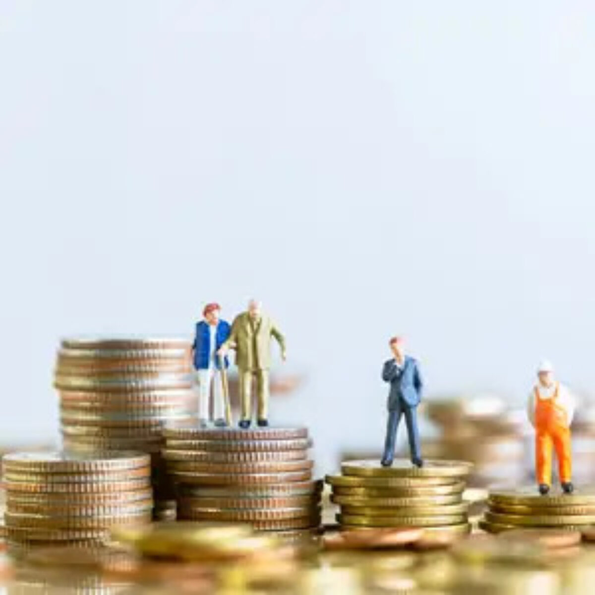Stacks of coins of various heights with figurines on an elderly couple, a businessman and a construction worker on top