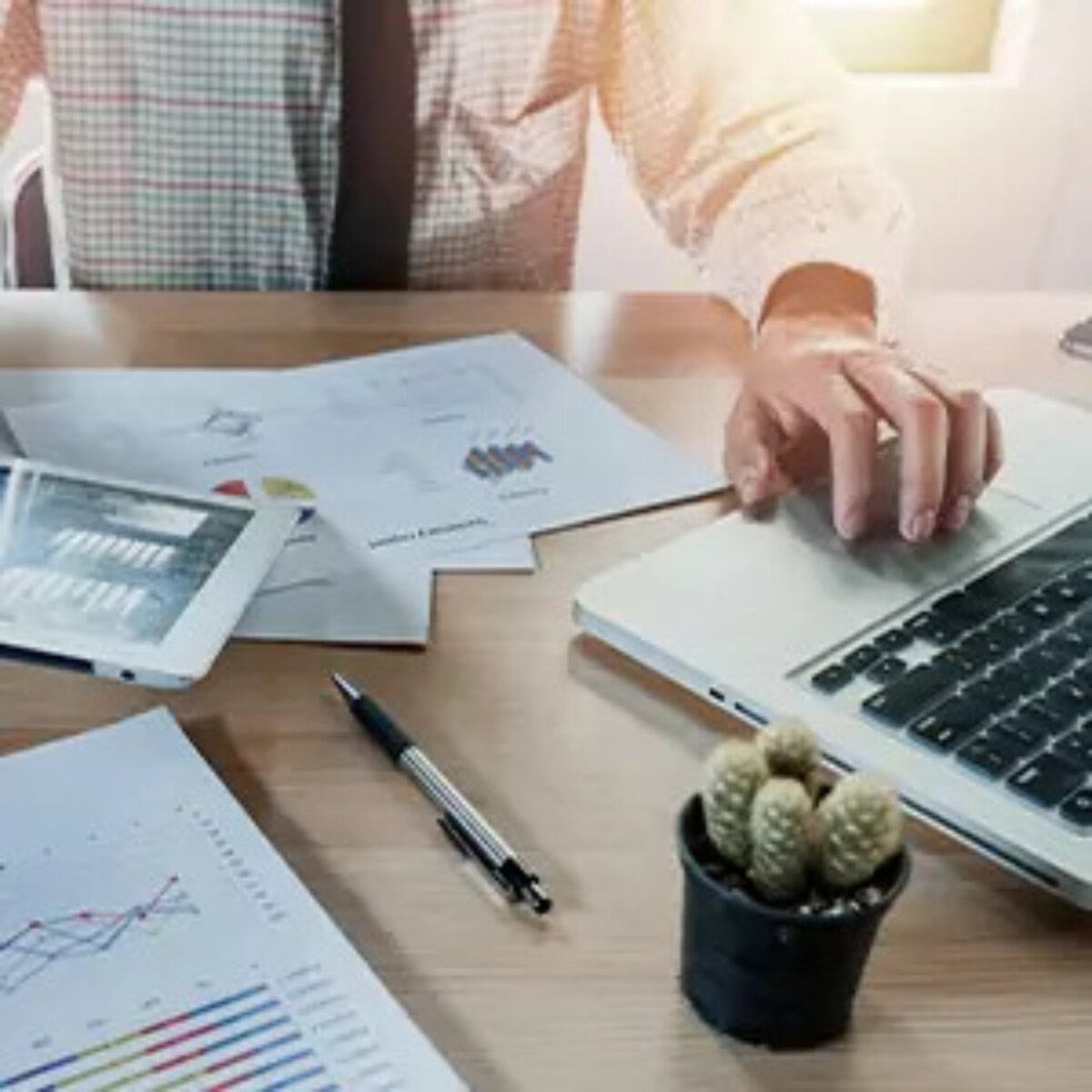 Businessman working on laptop at desk with papers