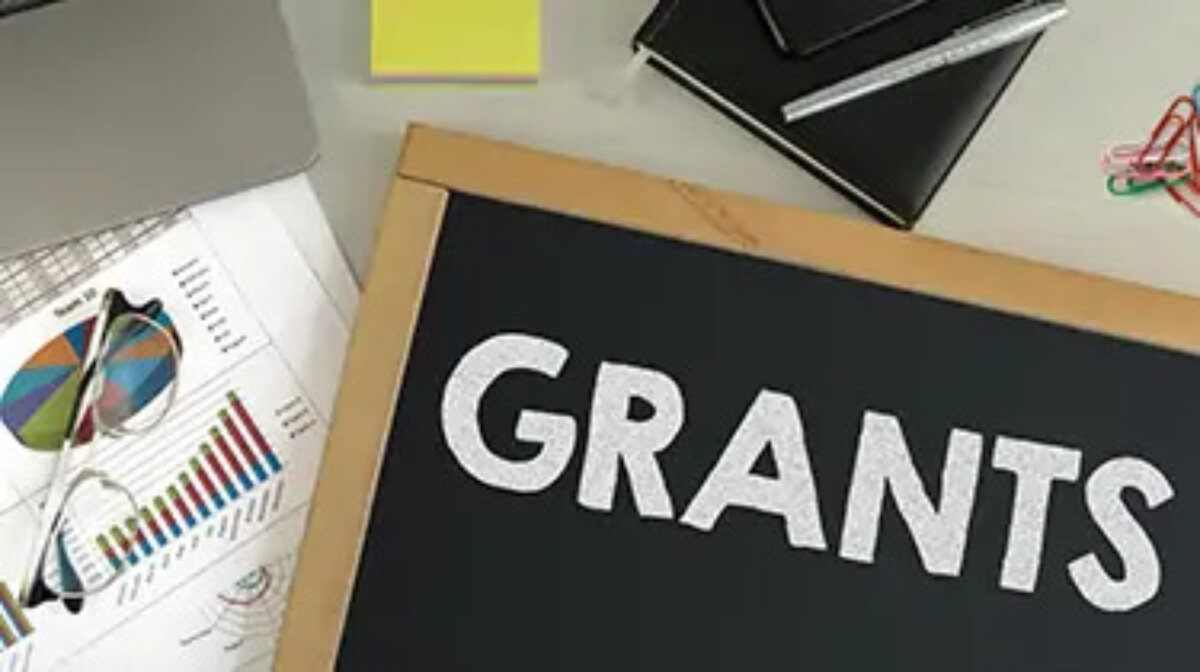Blackboard with 'Grants' written on it on top of paperwork