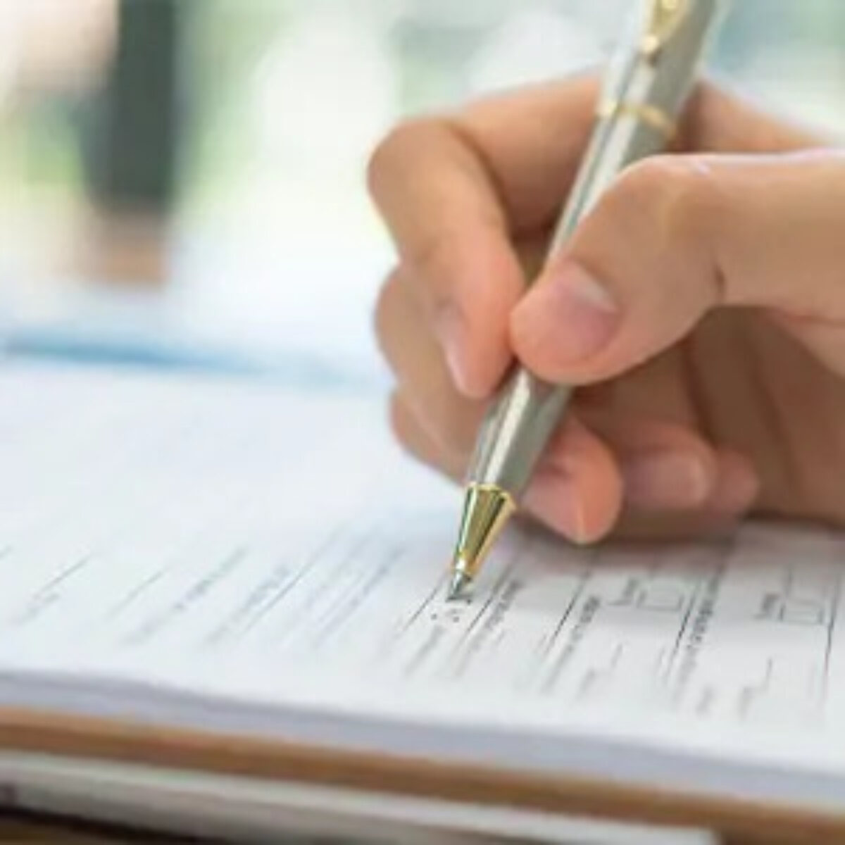 Hand filling out form with pen