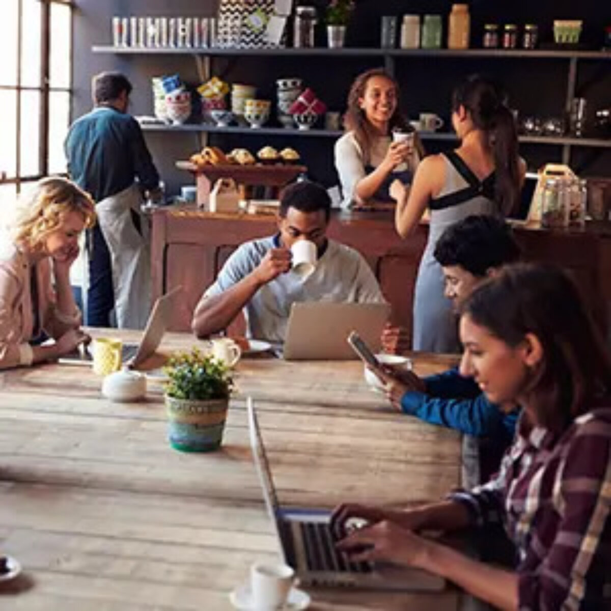 Group of businesspeople working independently at one table in coffee shop
