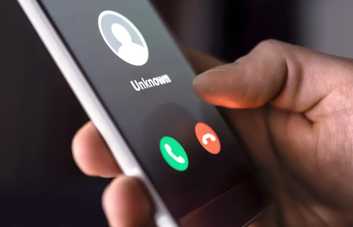 Hand holding smartphone displaying incoming call from unknown number