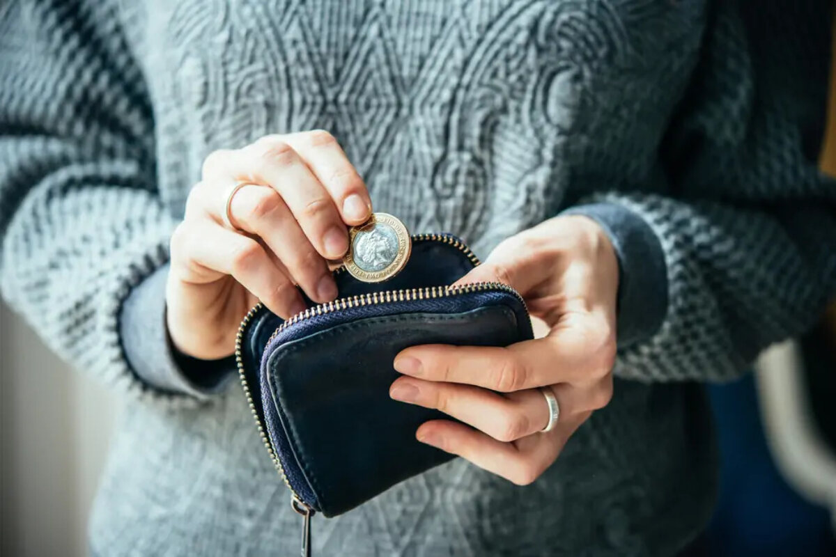 Woman putting a pound coin into a money pouch