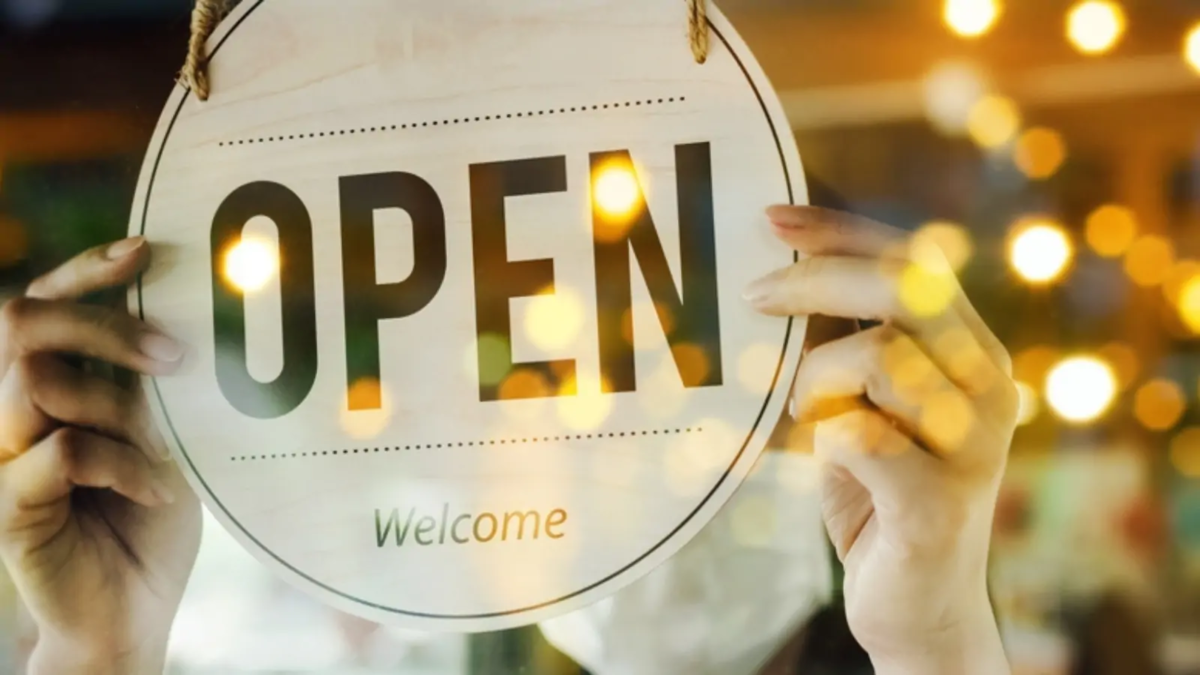 Small business owner turning over 'open' sign through window