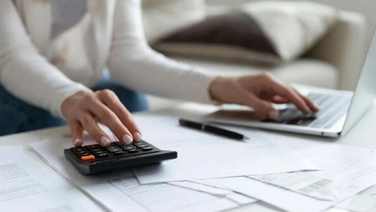 Businesswoman using calculator with one hand and laptop with the other