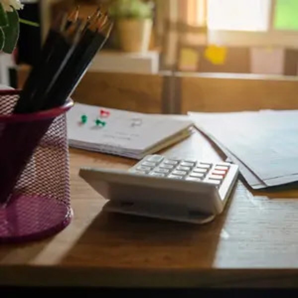 Calculator on desk next to pot of pencils and documents