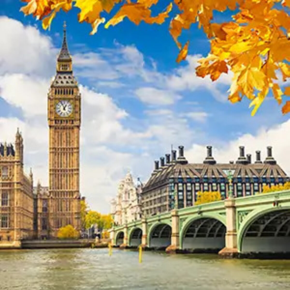 Big Ben and London Bridge against a blue sky and clouds with autumnal orange leaves in foreground