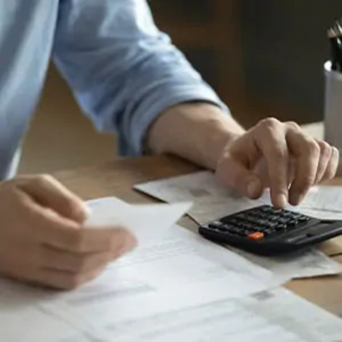 Businessman at desk using calculator and holding document to calculate tax payments