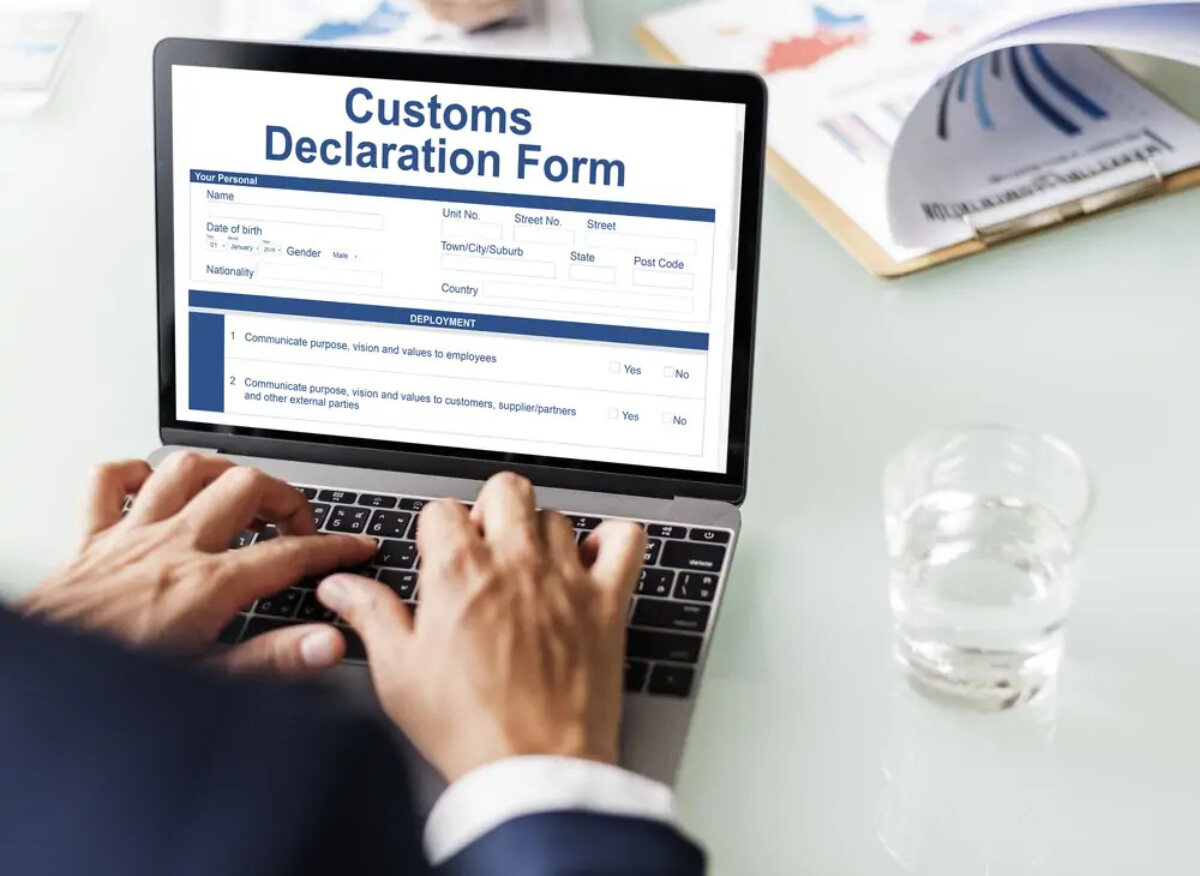 Businessman filling in Customs Declaration Form on laptop