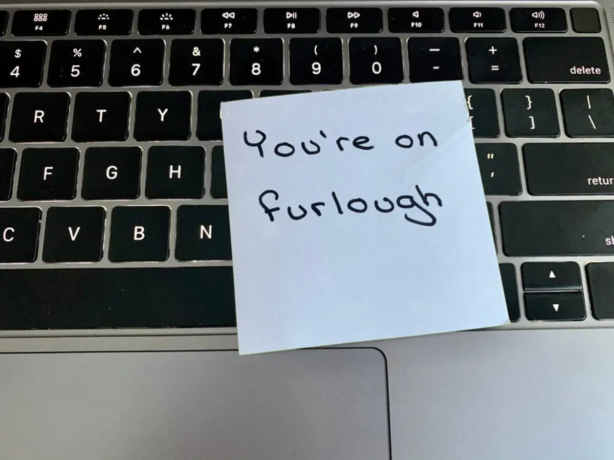 Laptop keyboard with post-it note on top that says 'you're on furlough'