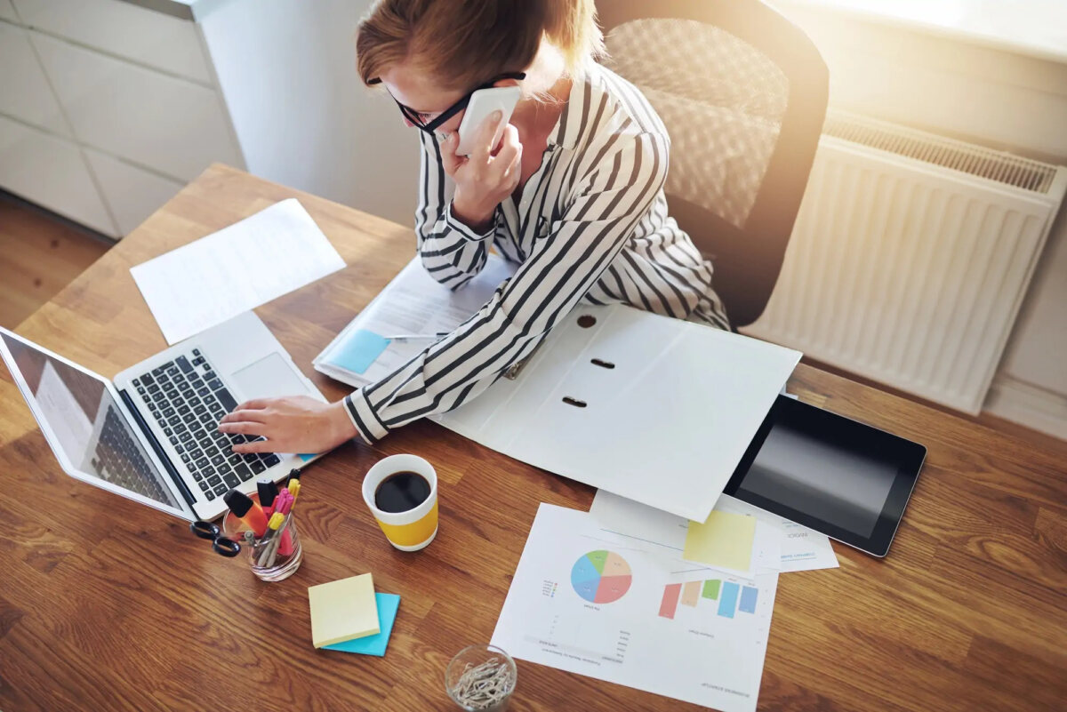Businesswoman taking a phonecall while using laptop at desk