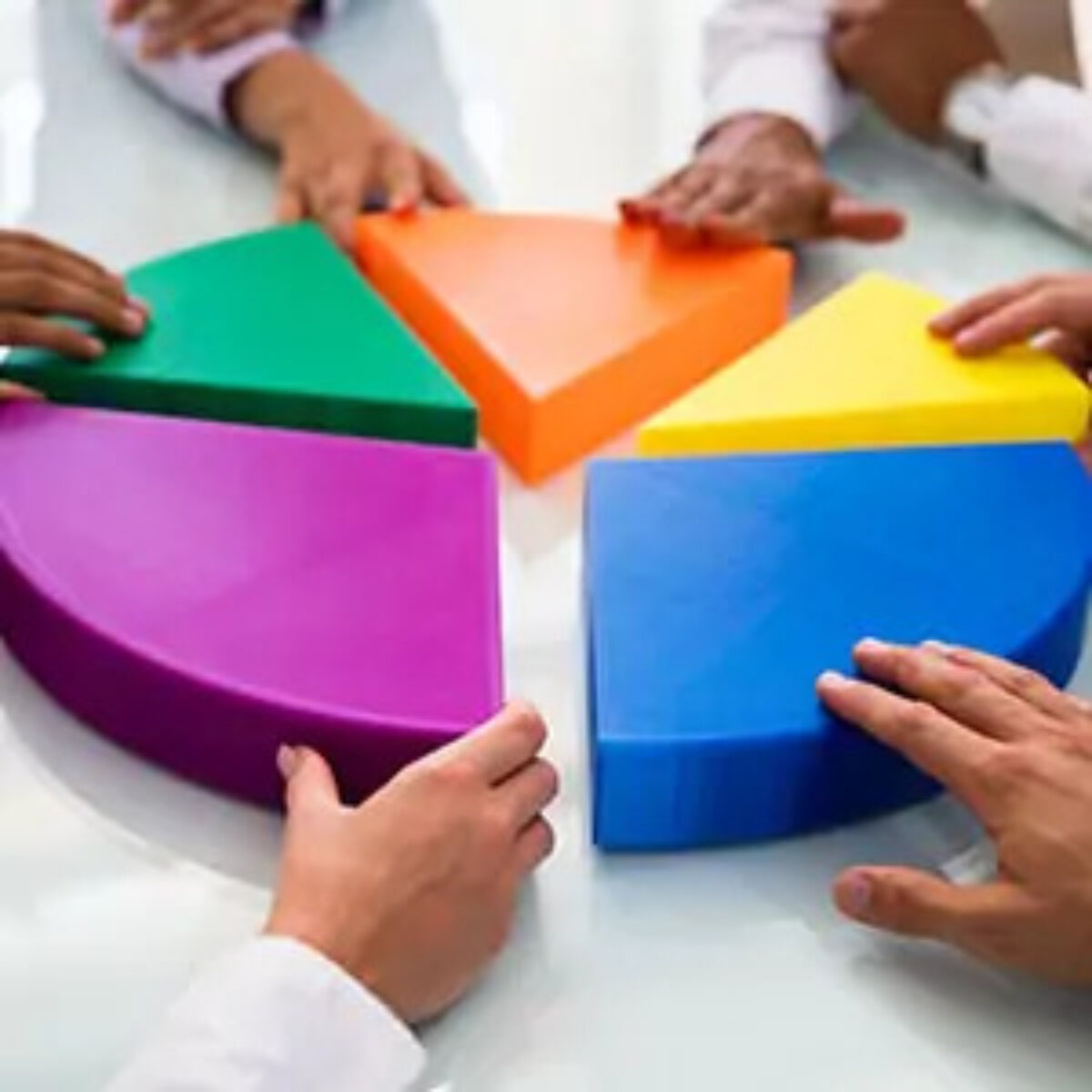 Hands pushing together five 3D sections of a pie chart