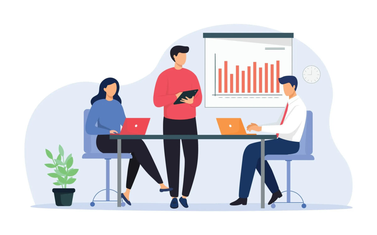 Cartoon of three businesspeople around table in meeting using laptops and tablets with a bar chart on wall behind